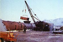 A crane shown loading contaminated ice into a large steel tank.