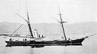 Small warship on flat sea, with smokestacks bent backwards.