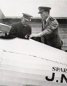 Two men standing over the interior of an airplane's cockpit.