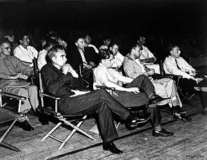 A group of men in shirtsleeves sitting on folding chairs.